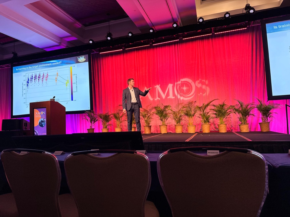 Daniel discussing the orbital-regime training comparison on stage at AMOS 2026